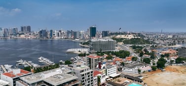 An aerial view of the Luanda skyline in Angola featuring modern high-rise buildings and a harbour with yachts under a bright blue sky, representing the established and diverse range of business entities in the region.