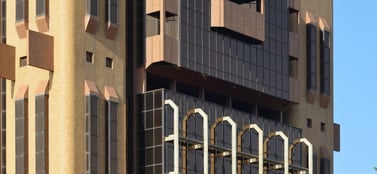 A close-up of the Central Bank of West African States building in Burkina Faso with dark glass facades and brown stone columns, representing the professional and structured range of business entities in the region.