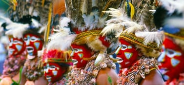 A close up of people in traditional Papua New Guinea ceremonial dress with vibrant face paint and intricate feather headdresses, representing the distinct and diverse range of business entities available in the region.